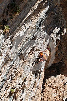 Female rock climber on handholds on challenging route on cliff