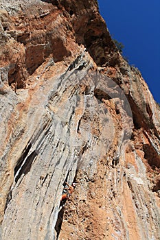 Female rock climber on handholds on challenging route on cliff