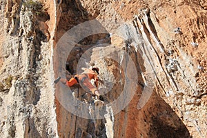 Female rock climber on handholds on challenging route on cliff