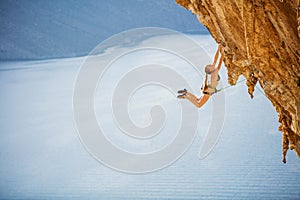 Female rock climber jumping on handholds on challenging route on cliff