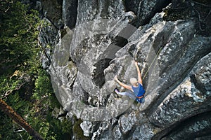 Female rock climber training rock climbing on a huge boulder