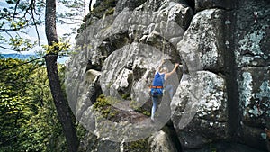 Female rock climber training rock climbing on a huge boulder