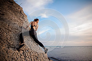 Female rock climber watching sunset over sea