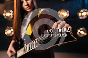 Female rock guitarist in suit tunes the guitar