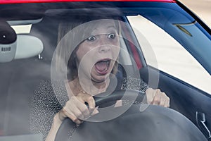 Female rookie new driver young beautiful woman scared and stressed while driving car in fear and shock photo