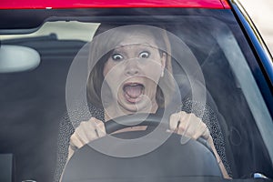 Female rookie new driver young beautiful woman scared and stressed while driving car in fear and shock photo