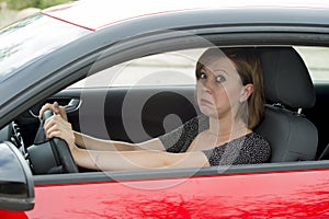 Female rookie new driver young beautiful woman scared and stressed while driving car in fear and shock photo