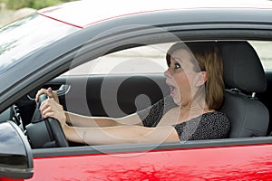 Female rookie new driver young beautiful woman scared and stressed while driving car in fear and shock photo