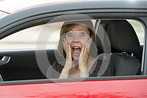 Female rookie new driver young beautiful woman scared and stressed while driving car in fear and shock photo