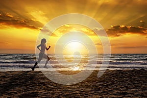 Female runner on a beach at sunset time
