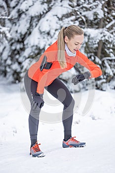 A female runner checks her sports performance using a smart watch. Running in winter and measuring heart rate