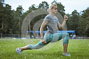 female runner doing lunge on green field