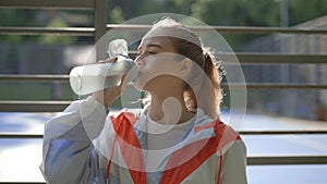 Female runner drinks water after training in sportswear. Young female runner feels thirsty after training. Sport and