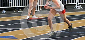 Female runner on an indoor track starting a relay race