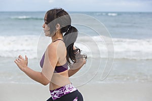 Female runner jogging during outdoor workout on the beach