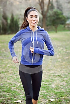 Female runner jogging during outdoor workout in a park.