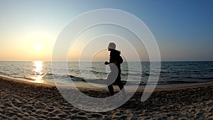 Female runner jogging on the sandy beach at sunset