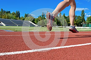 Female runner legs in shoes on stadium track, woman athlete running and working out outdoors, sport and fitness