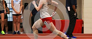 female runner running fast on an indoor track