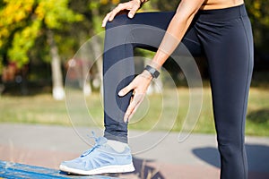 Female runner touching cramped calf at jogging