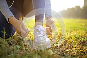 Female runner tying her shoes preparing for a jog outside at morning