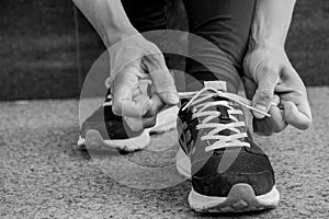 Female runner tying her shoes preparing for a run a jog outside black and white image