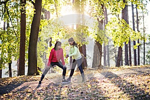 Female runners with smartwatch outdoors in forest in nature, checking the time.