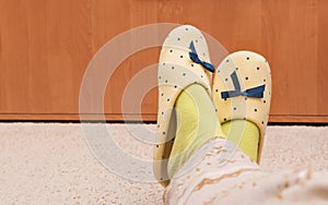 Female`s feet with yellow slippers and green socks