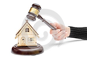 Female's hand holding judge's gavel and model of house on white background. Real estate law concept. House auction