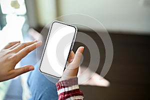 Female`s hand holding a mobile phone white screen mockup. close-up image