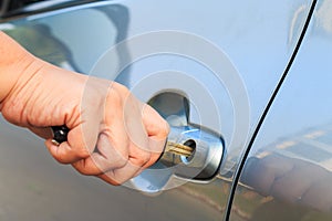 Female's hand opening a car door with car key.