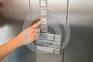 Female`s Hand Pressing First Floor Button In Elevator photo