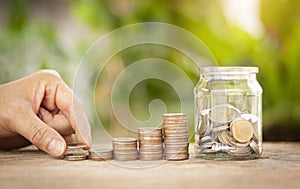 Hand putting stack coins for growing with green bokeh background. Financial, Investment, Business and Save Money concept