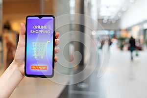 A female& x27;s hand shows a smartphone with a promo code for a discount on a purchase in an online store. Blurred background