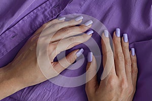 Female's hands with gelish manicure and nails of purple color