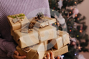 Female's hands in pullover holding many gift boxes.