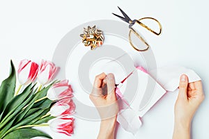 Female's hands unpack gift box next to scissors
