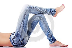 Female's legs in jeans on the floor. Side view.