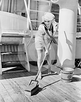 Female sailor swabbing boat deck