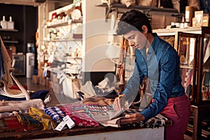 Female Sales Assistant Arranging Textiles In Homeware Store