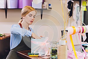 Female sales assistant working as florist and holding bouquet with customer in background. Horizontal shape, waist up.