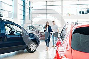 female sales manager showing red car to the customer