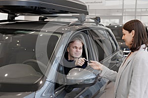 female salesperson and car rental helps with the purchase. signing a trade-in contract and handing over keys