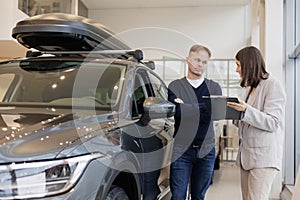 female salesperson and car rental helps with the purchase. signing a trade-in contract and handing over keys