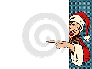 A female Santa Claus points to an empty space for a poster. Christmas and New Year. Winter seasonal holiday