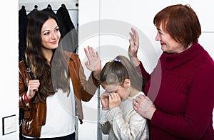 Female saying goodbye to senior woman with crying girl