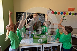 Female school teacher with a group of schoolchildren wearing green t shirts with a white recycling l