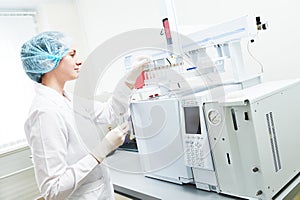 Female scientific researcher putting flask in Gas Chromatography