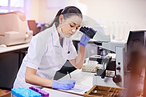 Female scientist, analyse and microscope in laboratory for research or notes with medical breakthrough. Doctor, data and photo