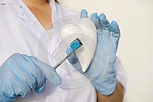 female scientist, doctor holding heart model, microprocessor, microchip, biochip tweezers for immunocytochemical studies heart,